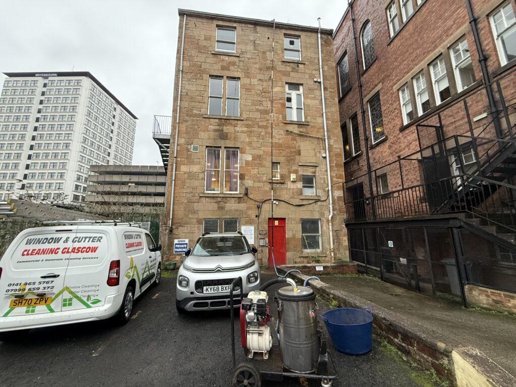 Narrow brick building with red door between urban streets.