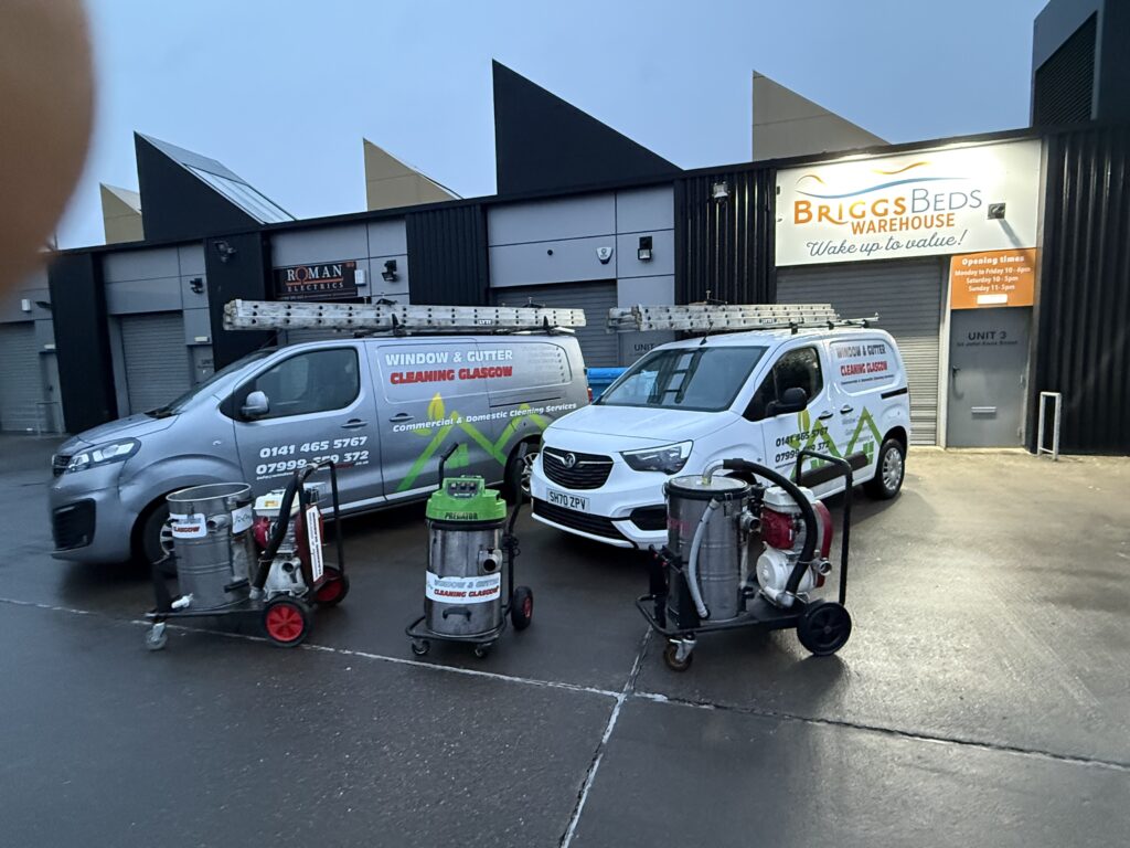 Two branded vans with cleaning equipment outside a business.