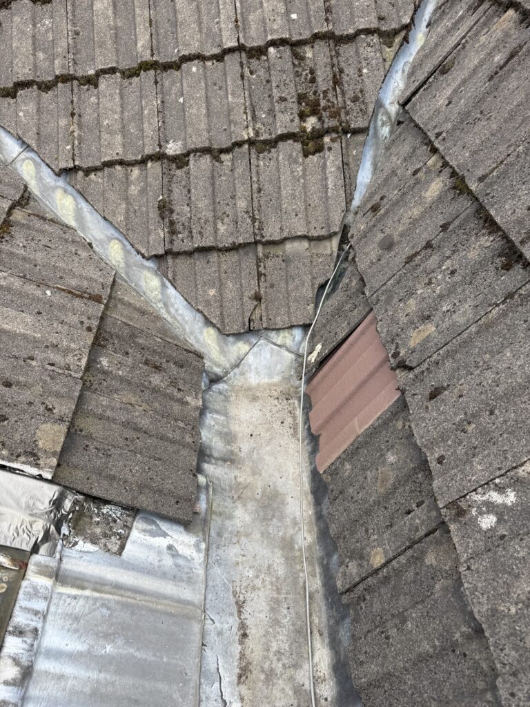 Close-up of a roof corner with tiles and a metal flashing.