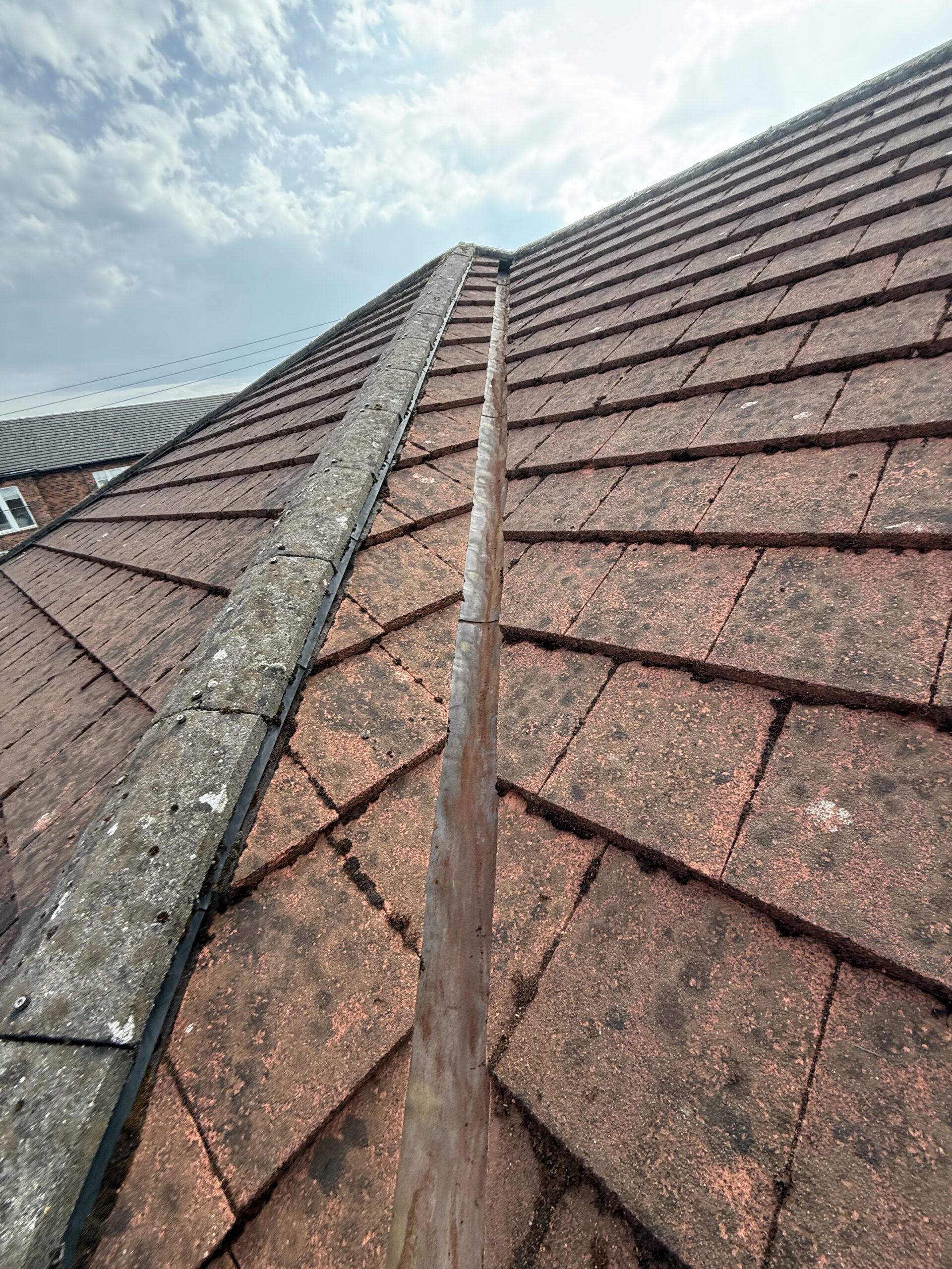Close-up of a weathered tiled roof with moss and dirt.