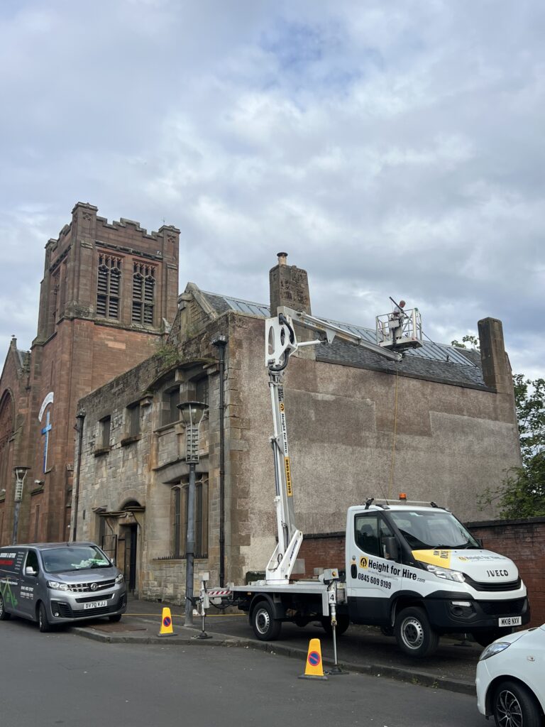 Old brick church building with trucks parked outside on a cloudy day.