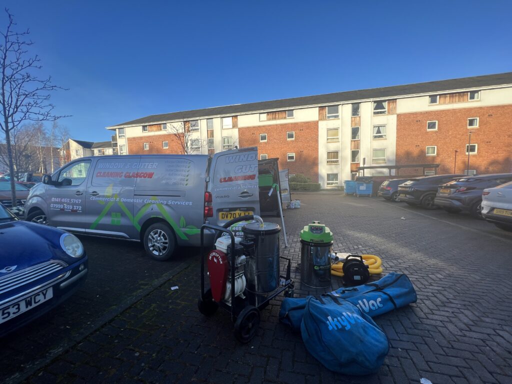 Moving supplies and packed boxes outside a residential building on a sunny day.
